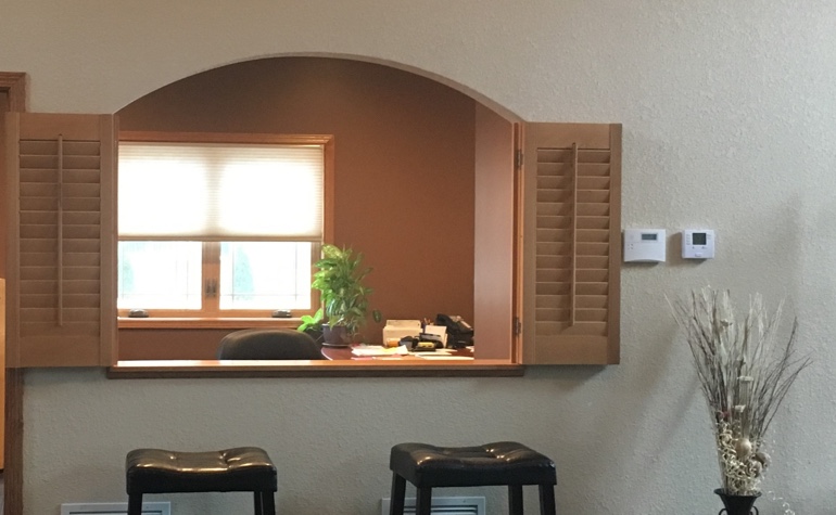 Shutters framing out a cutout between the kitchen and living room